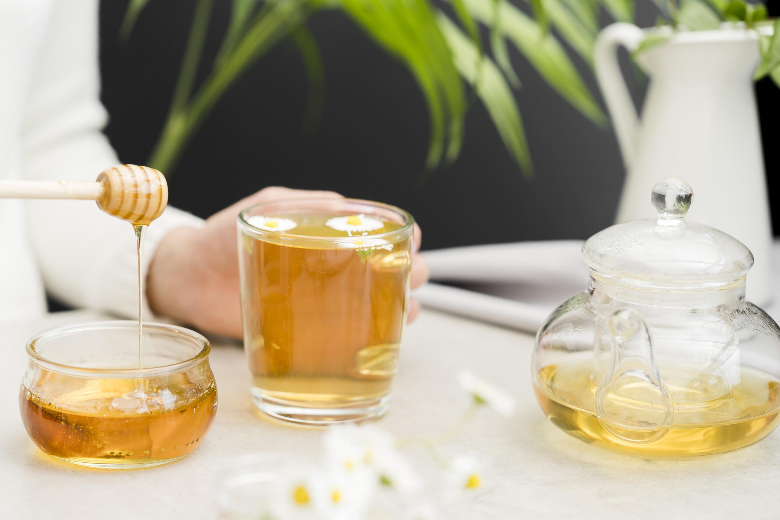 woman holding glass with tea honey dipper